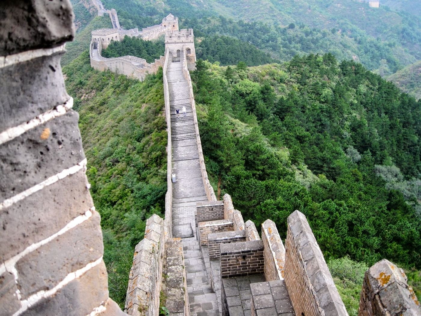 The Great Wall of China descending through forested hills